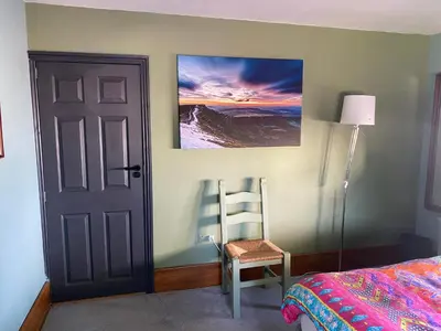 a bedroom with a door and a chair next to a bed at Mountain Suite, Stunning Views, Brecon Beacons in Llanhamlach
