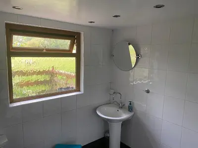 a bathroom with a sink and a mirror and a window at Mountain Suite, Stunning Views, Brecon Beacons in Llanhamlach