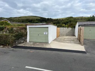 a garage with a green garage door in a driveway at Escapism Wales Gwalia in Llanrhystyd
