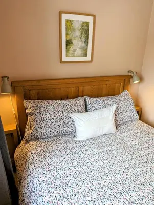 a bed with a wooden headboard and a white pillow at The Cob House. in Ifton Heath