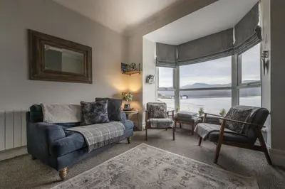 a living room with a couch and chairs and a large window at Harbour View - Flat 2 - Tudor House in Barmouth