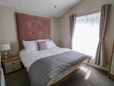a bedroom with a bed with a pink headboard and a window at Ystwyth 36 in Borth