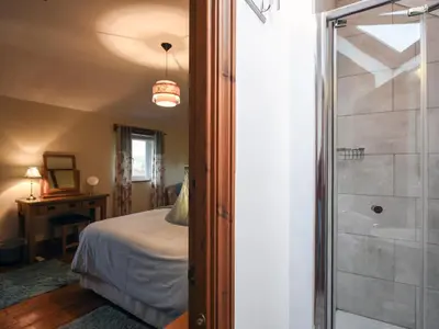 a bedroom with a bed and a bathroom with a shower at Heron Cottage in Bishops Castle