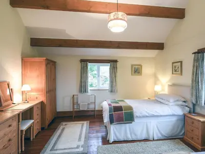 a bedroom with a bed and a desk and a window at Heron Cottage in Bishops Castle