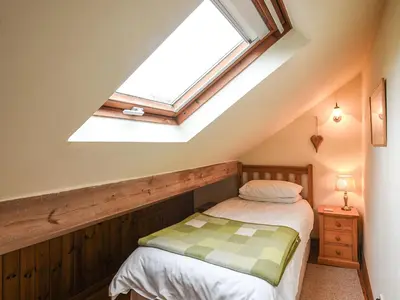 a attic bedroom with a bed and a skylight at Curlew Cottage in Bromlow