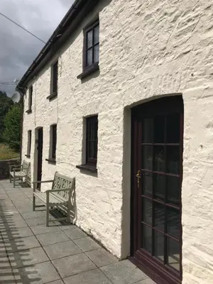 a white building with two benches and a door at Cobblers Cottage in Brecon Beacons in Brecon