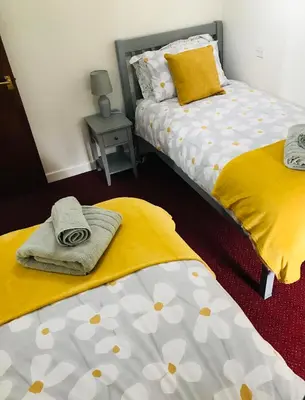 a bedroom with two beds with yellow and white sheets at Cobblers Cottage in Brecon Beacons in Brecon