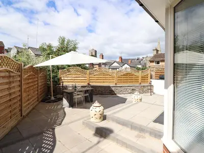 a patio with a wooden fence and an umbrella at Tan Y Ddol in Welshpool