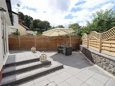 a patio with a table and an umbrella at Tan Y Ddol in Welshpool