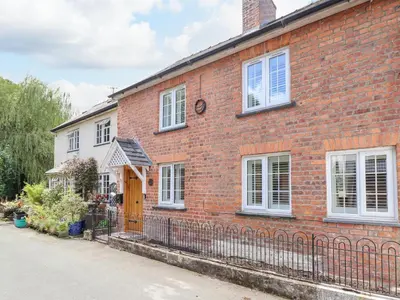 a brick house with a fence in front of it at Tan Y Ddol in Welshpool