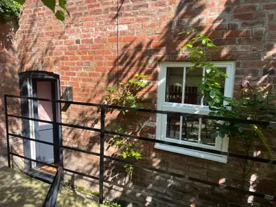 a brick building with two windows and a fence at The Gardener's Cottage in Leominster