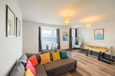 a living room with a couch with colorful pillows at Seafront apartment with balcony, parking and sea views in Aberystwyth