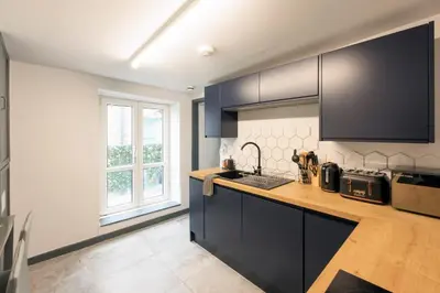 a kitchen with black cabinets and a counter top at Seafront apartment with balcony, parking and sea views in Aberystwyth