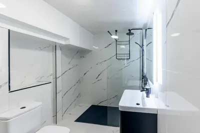 a white bathroom with a shower and a sink at Seafront apartment with balcony, parking and sea views in Aberystwyth