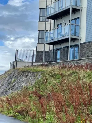 a building on top of a cliff next to the ocean at The New 2 Plas Morolwg in Aberystwyth