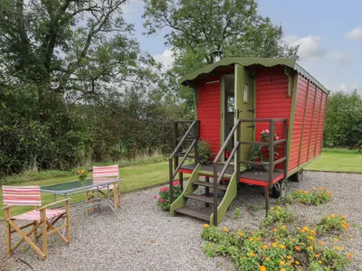 a red tiny house with a table and chairs at Tilly Gypsy-style Caravan Hut in Brecon