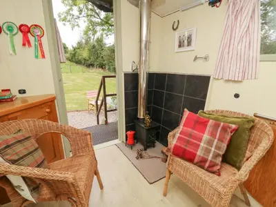 a living room with a fireplace and wicker chairs at Tilly Gypsy-style Caravan Hut in Brecon