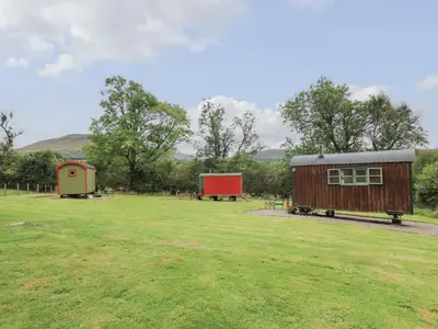 a field with two smallsheds in the middle of it at Tilly Gypsy-style Caravan Hut in Brecon