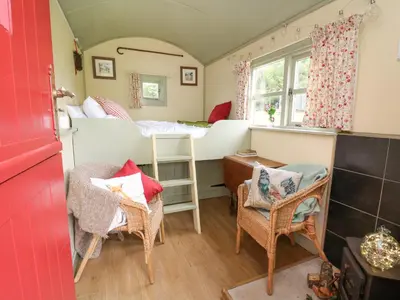 a room with a bed and chairs and a table at Sweet Briar Shepherds Hut in Brecon