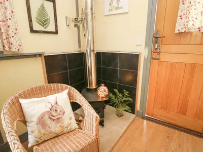 a wicker chair with a pillow with a cat on it at Brown Hare Shepherds Hut in Brecon