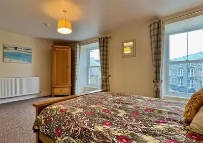 a bedroom with a large bed with a flowered blanket at Luxury 4 Bedroom Seaside Apartment - Glan Y Werydd House in Barmouth