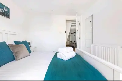 a white bedroom with a bed with a green rug at The Cwtch in Brecon