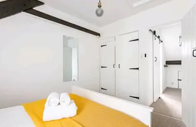 a bedroom with white walls and a bed with towels at The Cwtch in Brecon