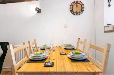 a wooden table with plates and glasses and a clock on the wall at The Cwtch in Brecon