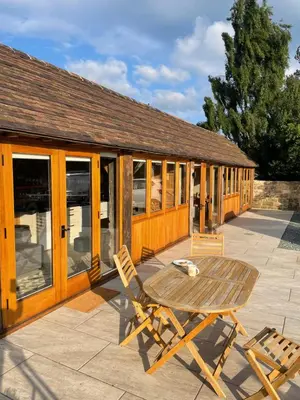 a patio with a table and chairs in front of a building at Beautiful countryside Byre conversion in Shrewsbury
