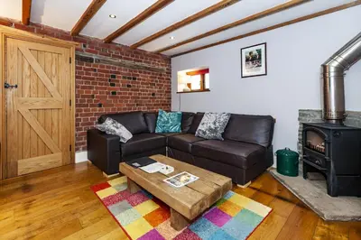 a living room with a leather couch and a wood stove at The Agents House, Bed & Breakfast in Hay-on-Wye