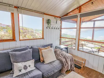 a living room with a blue couch and windows at Top Of The World Lodge in Aberdyfi