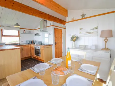 a kitchen with a table with white plates and a bottle of wine at Top Of The World Lodge in Aberdyfi