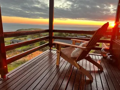 a rocking chair on a deck with a view of the ocean at Top Of The World Lodge in Aberdyfi