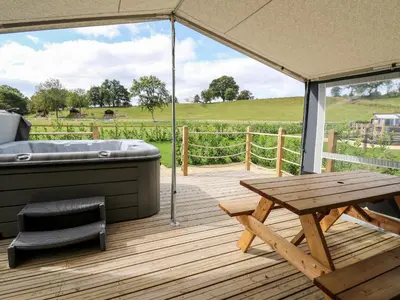 a deck with a hot tub and a picnic table at The Otter in Rhayader