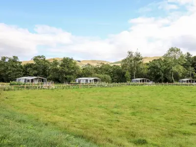 a field with a farm with trees and buildings at The Otter in Rhayader