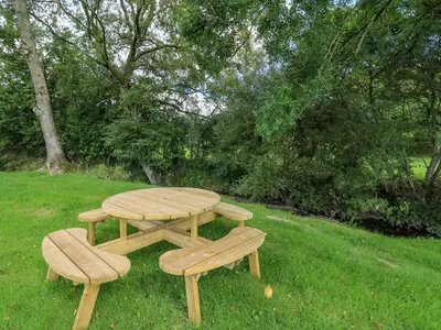 a wooden picnic table and two benches in the grass at The Heron in Rhayader