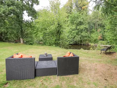 two wicker tables in a park with a bench at Riverside Rest in Builth Wells