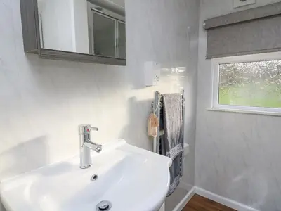 a white bathroom with a sink and a window at Riverside Rest in Builth Wells