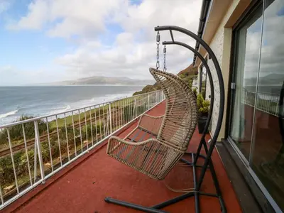 a swinging bench on a balcony overlooking the ocean at Machlud Haul in Llwyngwril