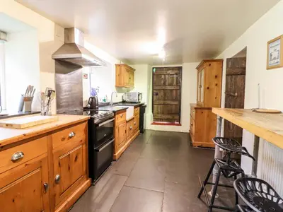 a kitchen with wooden cabinets and a black stove top oven at Gwengraig in Dolgellau