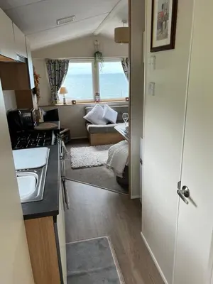 a kitchen with a sink and a living room at Barmouth Pet-Friendly 2-Bed Caravan with Sea View in Barmouth