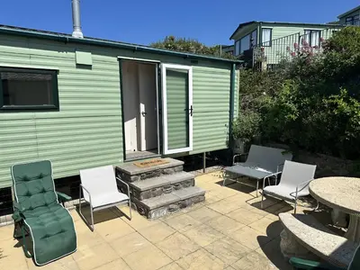 a patio with chairs and tables and a building at Barmouth Pet-Friendly 2-Bed Caravan with Sea View in Barmouth