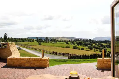 a patio with a table and a view of a field at Burrow View in Rhayader