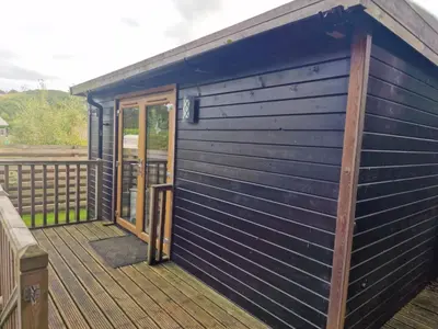 a blue building with a door on a deck at Glamping Hut - Sleeps 2 hot tub & parking in Welshpool