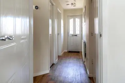 a hallway with white walls and wooden floors and a door at Fair View - Off Street Parking and Garden in Shrewsbury