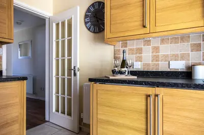 a kitchen with wooden cabinets and a clock on the wall at Fair View - Off Street Parking and Garden in Shrewsbury
