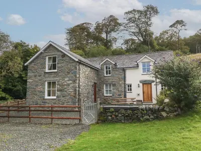 a stone house with a fence in front of it at Tyn Llwyn in Talsarnau