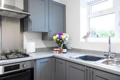 a kitchen with white cabinets and a sink and flowers at Fair Haven - Off Street Parking and Garden in Shrewsbury
