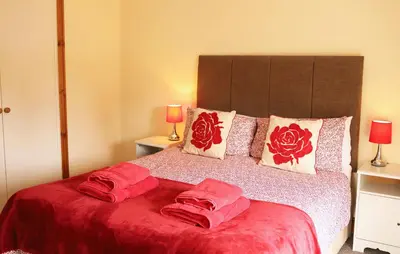 a bedroom with a bed with red sheets and pillows at Pet-Friendly Logburner Horse Stable Views in Hay-on-Wye