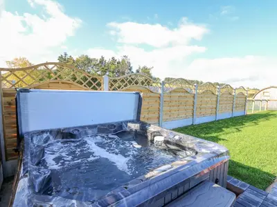 a hot tub in a backyard with a fence at Poppy in Rhayader